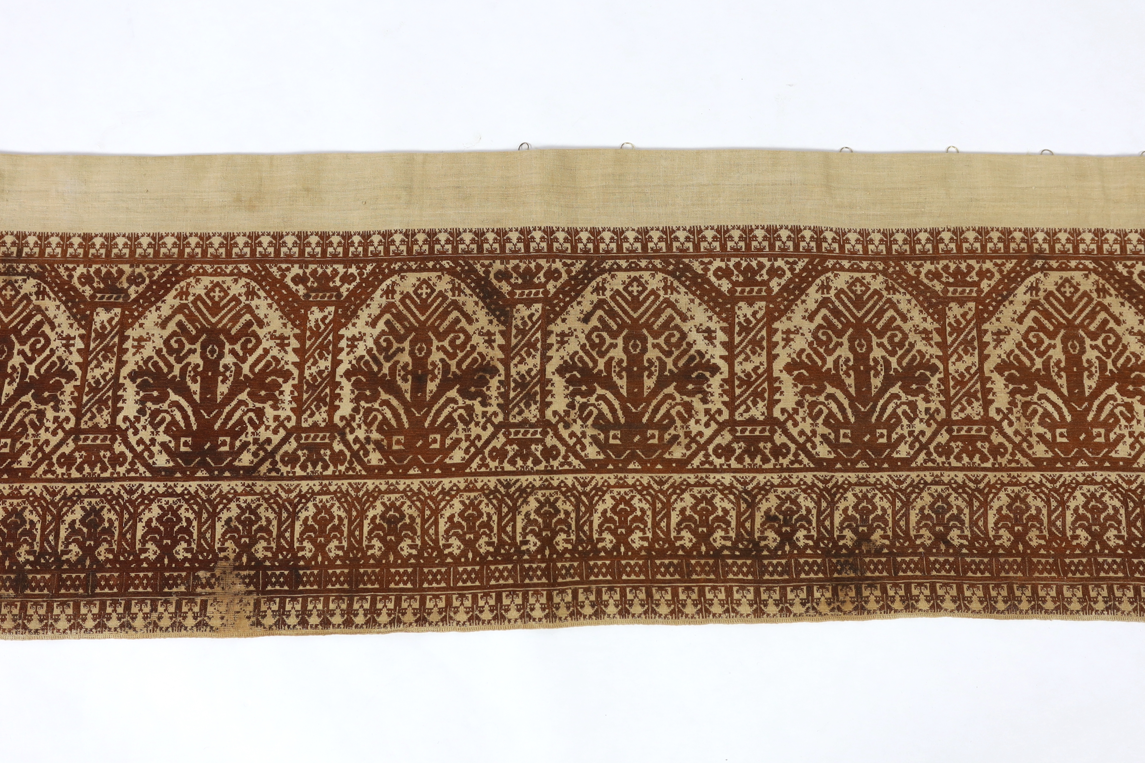 An early 19th century long Greek Islands cross stitch pelmet (hanging), embroidered on coarse linen with brown silk, using cross stitch, designed in horizontal rows of similar symbols, the lower row being a smaller size,